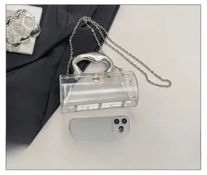Détail du sac cylindrique en acrylique transparent avec poignée et chaîne argent