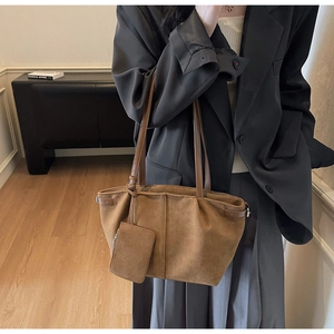 Detail of brown faux suede tote bag with matching pouch shown on a professional outfit