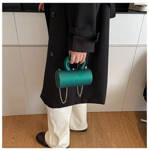 Gros plan sur le sac de soirée cylindrique vert émeraude avec chaîne dorée et anse en U