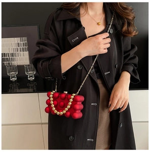 Detail of red spherical texture evening bag with gold beaded handle and metal chain