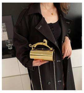 Detail of golden cylindrical evening bag with leopard handle and metal chain strap