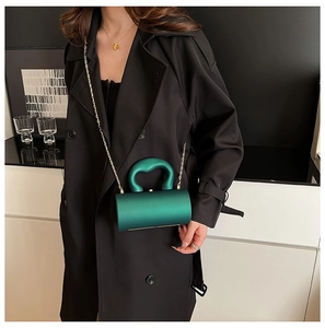 Pochette cylindrique en acrylique vert avec poignée ondulée et chaîne dorée sur manteau