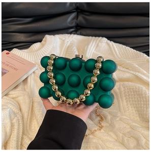 Detail of dark green textured eggshell clutch with gold bead handle and chain strap