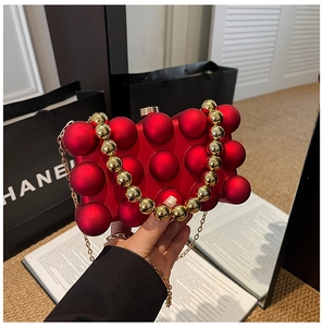 Detail of red egg-shaped evening bag with spherical texture and golden chain