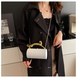 Close-up of white cylindrical acrylic evening bag with gold leopard handle and chain strap