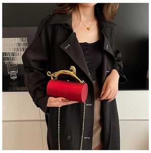 Detail of red cylinder evening bag with gold leopard handle and sleek metal chain