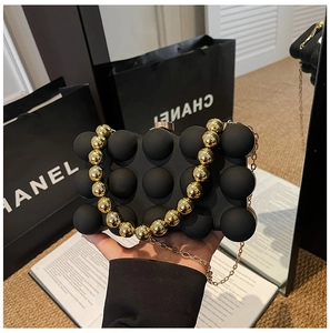 Detail of black 3D textured ball evening clutch with gold beaded handle and metal strap