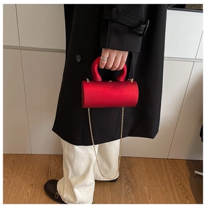 Détail de la pochette de soirée cylindrique rouge avec poignée et chaîne dorée