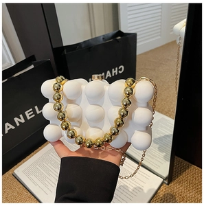Detail of white acrylic eggshell clutch with bubble texture and gold bead handle