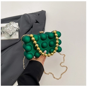 Detail of dark green bubble texture acrylic evening bag with gold sphere handle and chain