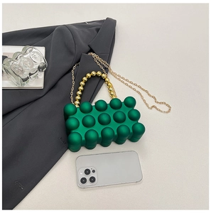 Detail of green acrylic egg-shaped evening bag with bubble texture and gold chain strap