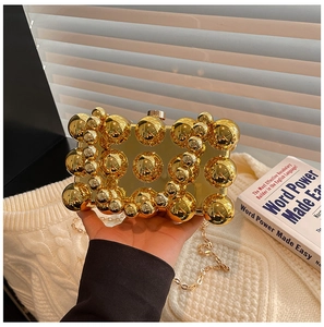 Detail of a gold metallic evening clutch with 3D sphere texture and detachable chain strap