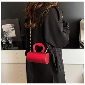 Détail de la pochette cylindrique rouge en acrylique avec bandoulière chaîne dorée