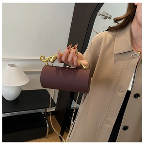 Detail of luxury acrylic cylinder bag with golden leopard handle and chain on trench coat