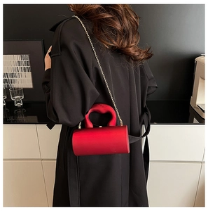 Gros plan d'un sac cylindrique rouge vif avec poignée circulaire et chaîne dorée