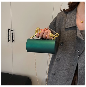 Detail of emerald green cylinder evening bag featuring a luxury gold leopard handle