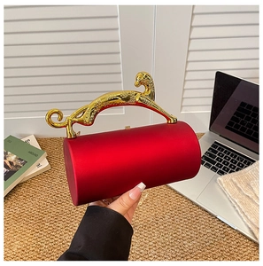 Detailed close-up of a red cylinder evening bag with a gold leopard handle and chain
