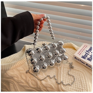 Detail of silver mirrored eggshell clutch with metallic studs and beaded handle