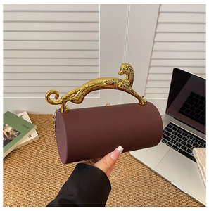 Detail of luxury burgundy evening bag with golden leopard handle and metal chain strap