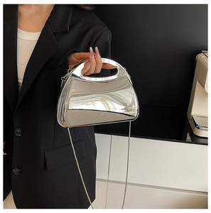 Detail of silver metallic mirror clutch with integrated top handle and detachable chain strap