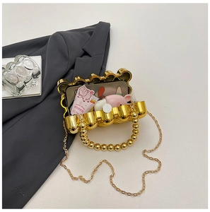 Inside view of ripple pattern gold evening clutch holding smartphone and cosmetics