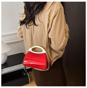 Model wearing a red metallic evening bag with gold ring handle and chain strap
