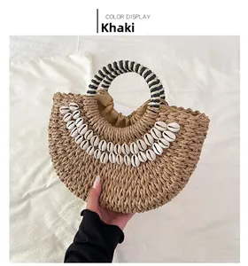 Detail of khaki straw handbag with white cowrie shells and striped woven handle