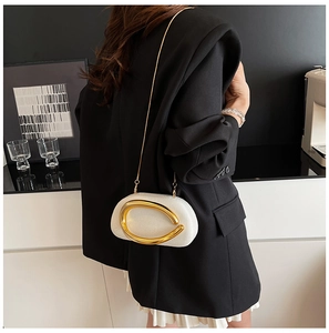 Detail of white textured mini bag featuring a large golden C-shaped metallic buckle and chain