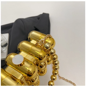 Detail of golden acrylic capsule dinner bag with beaded handle and metallic finish
