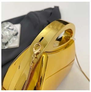 Detailed close-up of the polished gold metal handle and chain attachment on evening clutch