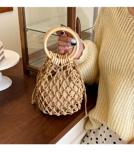 Detail of hollow woven beach bag with round wooden handles and drawstring pouch