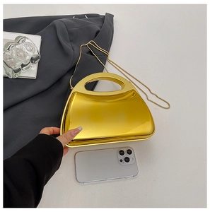 Detailed scale view of a mini gold metallic evening bag with chain and phone comparison
