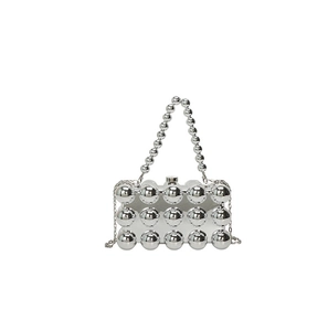 Detailed view of a silver acrylic evening clutch with 3D studs and metallic bead handle