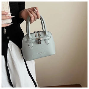 Detail der hellblauen Muschelhandtasche mit Litschi-Maserung und goldenem Schloss