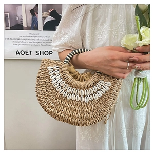 Detail of shell-decorated straw tote bag featuring contrast handles and drawstring liner