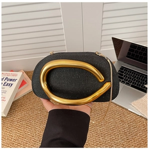 Detail of black woven evening bag with elegant gold metal handle and chain strap