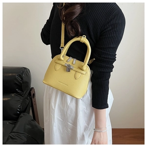 Detail der gelben Handtasche aus genarbtem Leder mit Metallschloss und verstellbarem Gurt