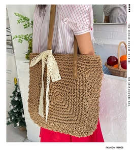 Detail view of woven raffia tote bag with white lace bow and brown leather straps