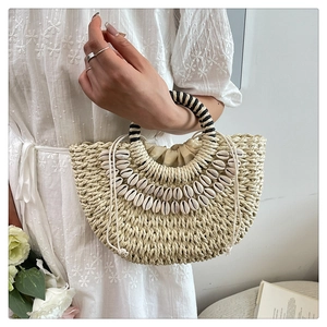 Detailed close-up of handmade shell straw handbag with woven handles and drawstring liner