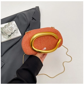 Close-up of orange woven clutch with large gold metal handle and chain strap