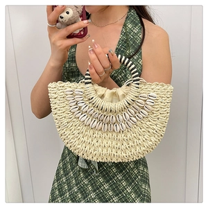 Detail of straw handbag with shell decor and black and white woven handle