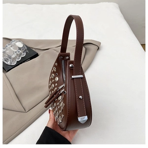 Close-up of a brown leather Hobo bag featuring silver metal rivets and a crescent shape