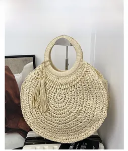 Detail of round straw bag with decorative tassel and circular top handle in cream white