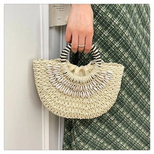Detail of handmade straw bag with sea shells, ring handles and drawstring inner lining
