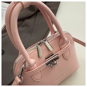 Makro-Detail der rosa Muschel-Tasche mit Litschi-Textur, Doppelreißverschluss und Metallschloss