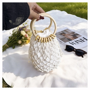 Detail of hand-woven cotton beach bag featuring round wooden handles and drawstring liner