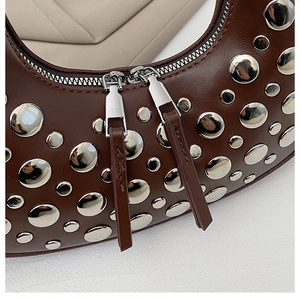 Close-up of brown leather shoulder bag with silver studs and dual zipper details
