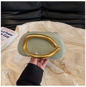Detail of light green tweed evening bag with bold gold metal handle on white sweater