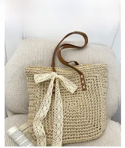 Detail of raffia woven tote featuring large lace bow and premium brown leather handles