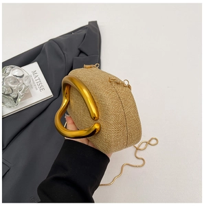 Detailed view of woven straw evening bag with U-shaped gold metal handle and chain strap